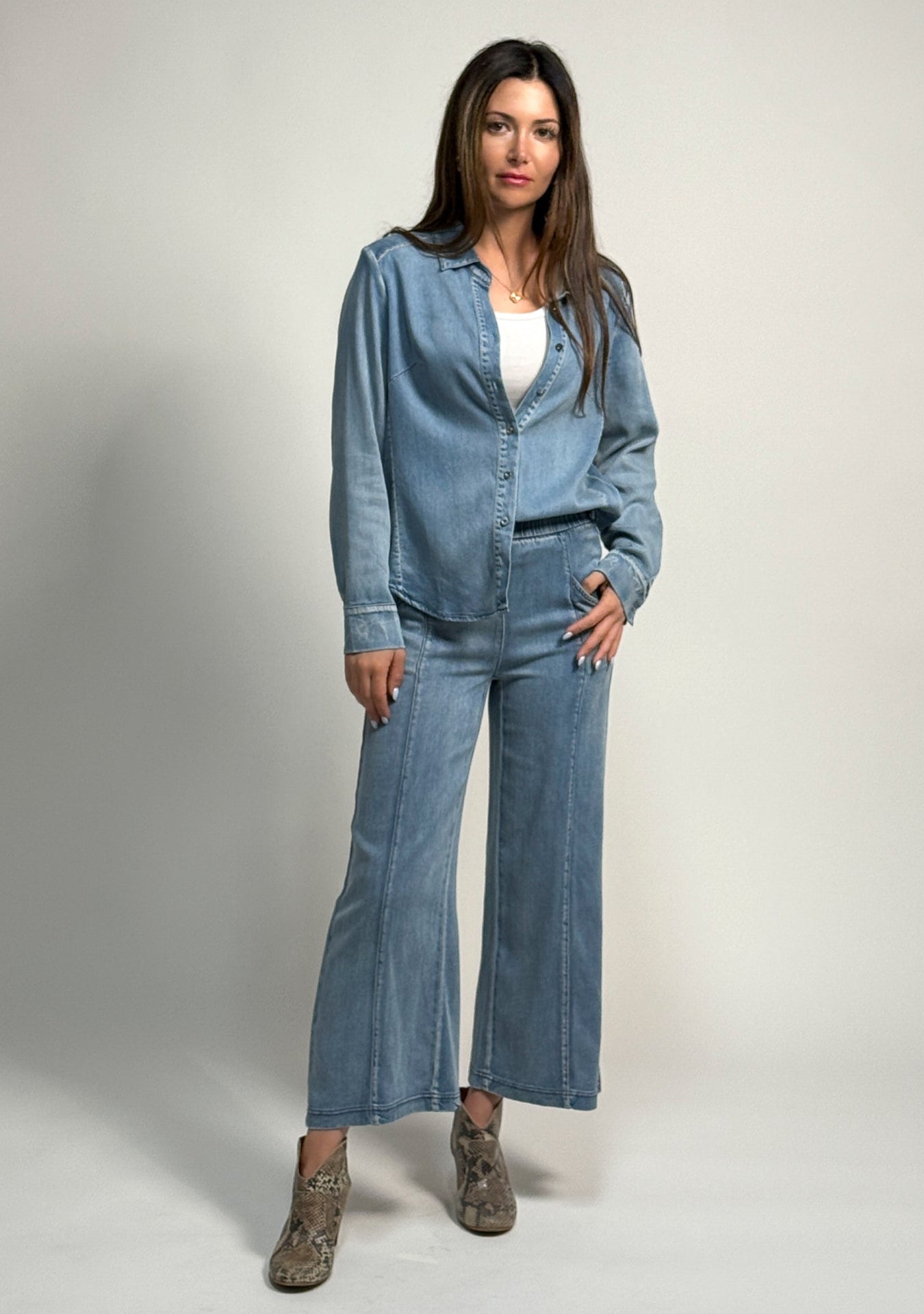 Woman wearing a denim outfit featuring the alex shirt and whitley pant by inlarkin on a plain background