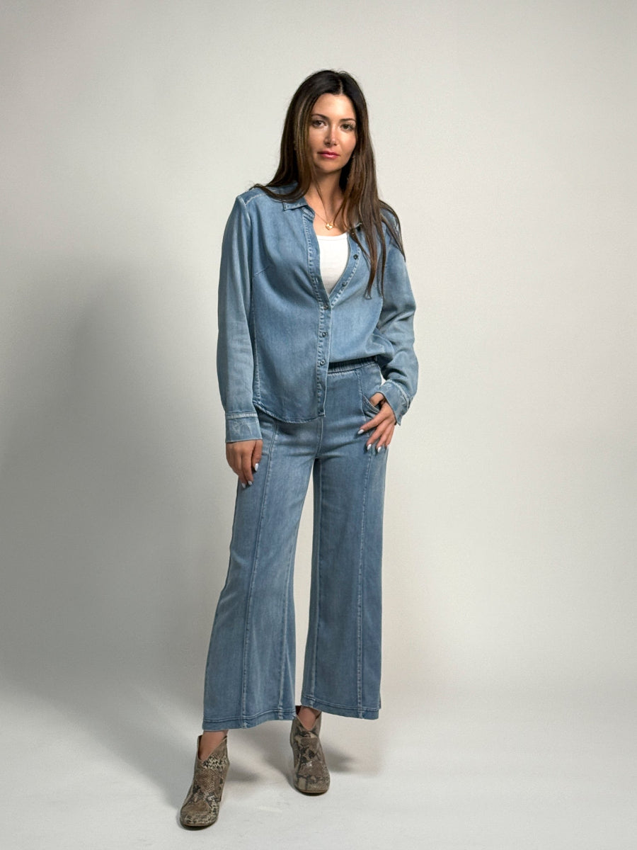 Woman wearing the alex denim shirt paired with the denim whitley pant by inlarkin on a light gray backdrip