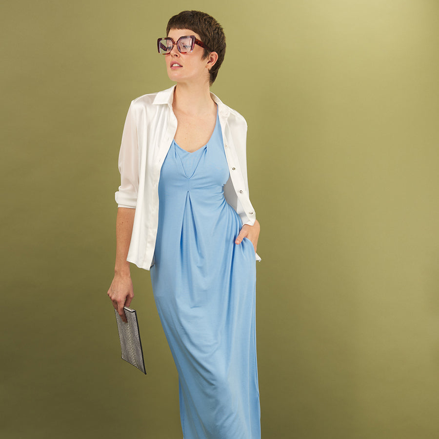 Woman wearing a light blue royal tuck dress with a white aliferous shirt by inlarkin on a green background