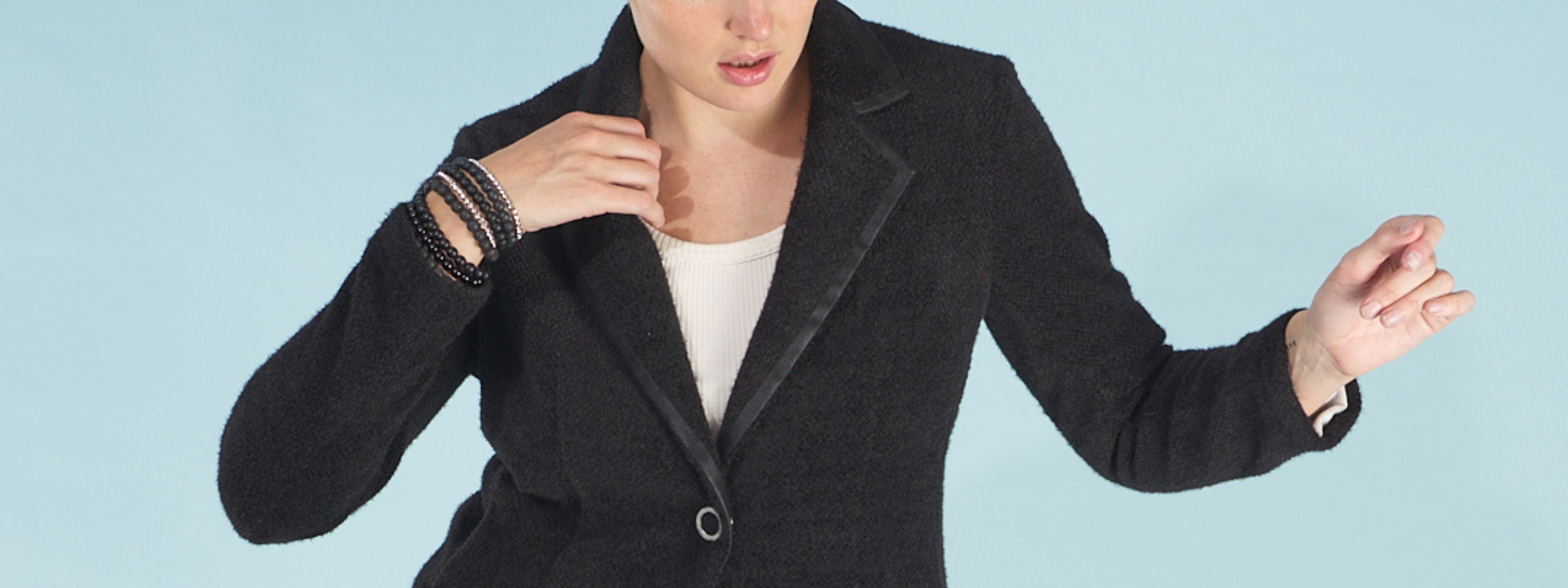 Woman wearing a black austin blazer by inlarkin over a white shirt on a light blue background