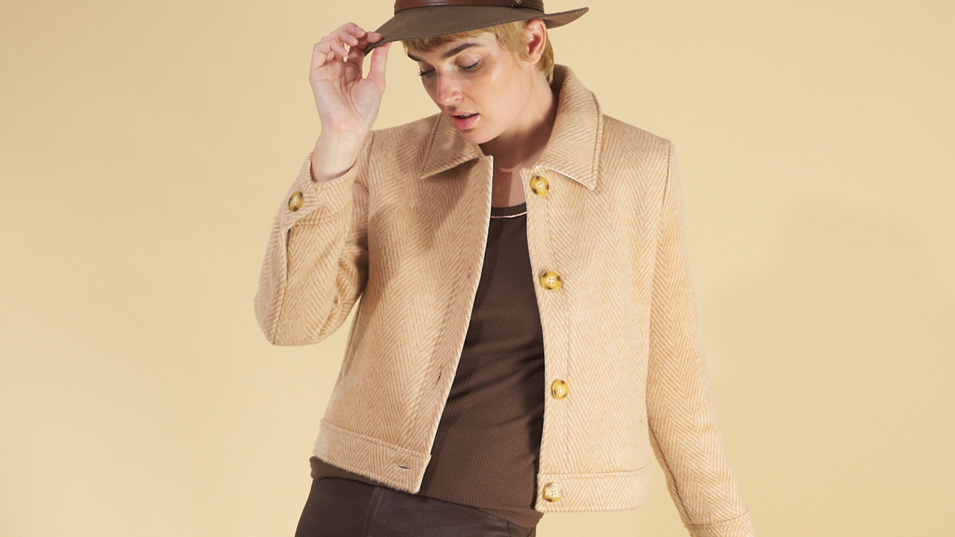 woman wearing the herringbone harriet jacket by inlarkin and brown bootleg jeans