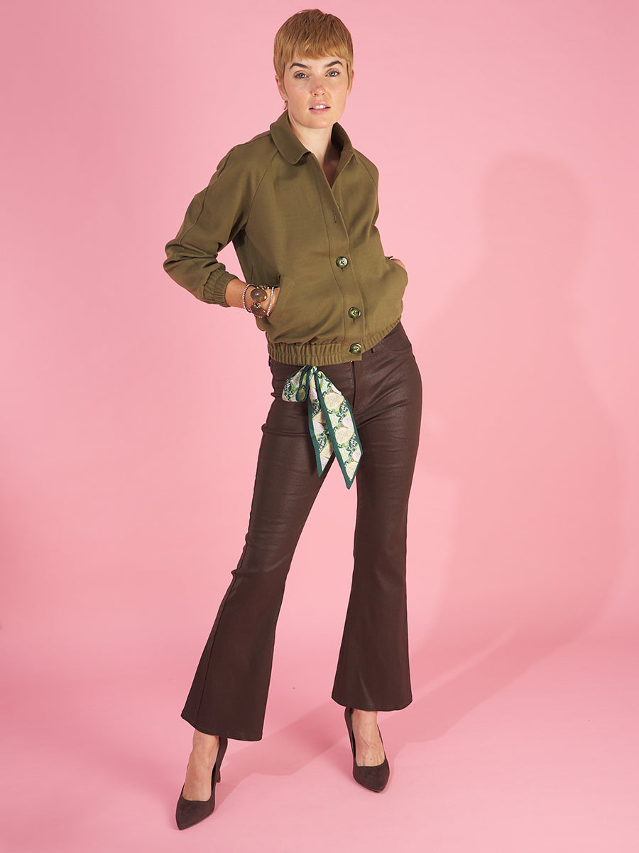 lady bomber jacket front view in olive by inlarkin showing the seaglass buttons, butterfly collar, pockets and gathered hem paired with the gloss bootleg in chocolate with bootleg flare and front pockets