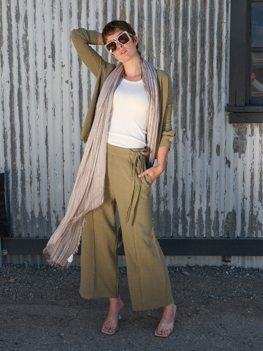 Woman wearing a sage green linen fray shirt and pant by inlarkin against a green background