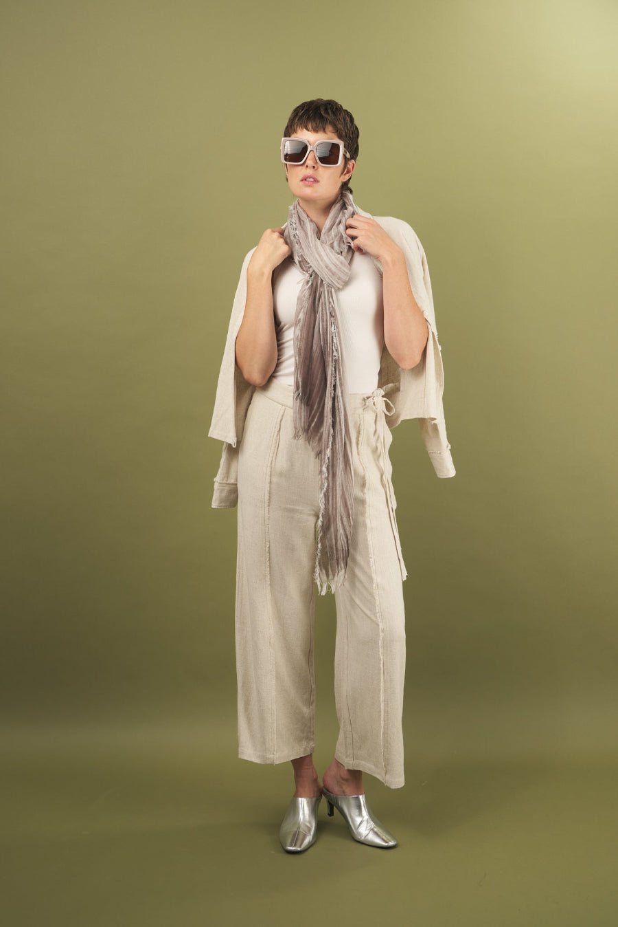 Woman wearing a sand linen fray shirt and pant by inlarkin against a green background