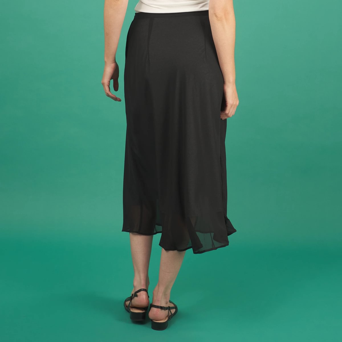 a black midi length slay skirt by inlarkin back view with a sheer layer at the hem and side pockets