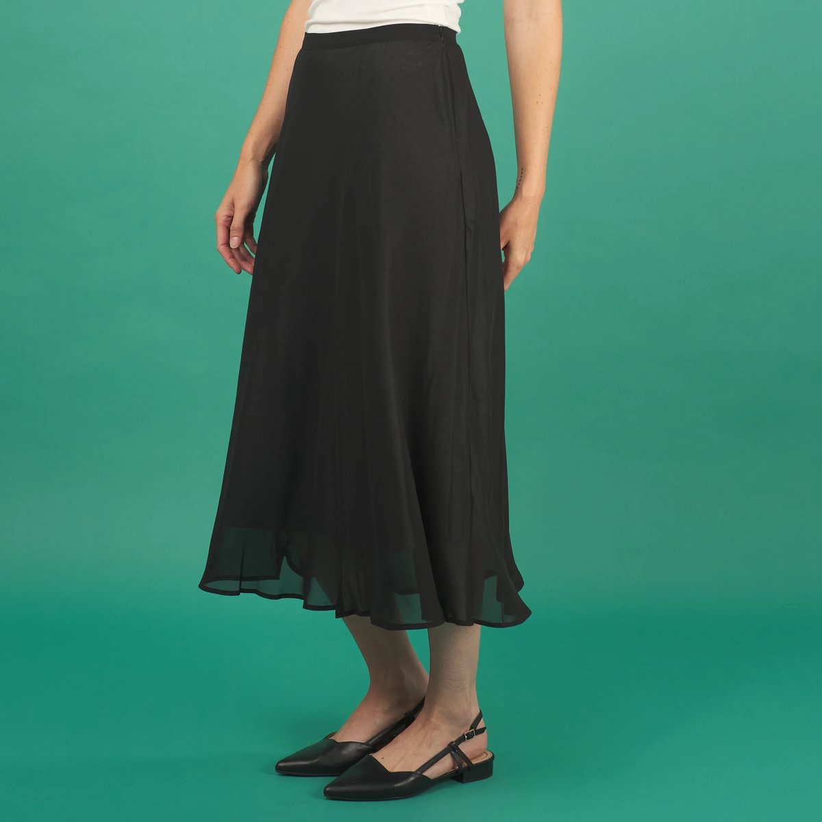 a black midi length slay skirt by inlarkin side view with a sheer layer at the hem and side pockets