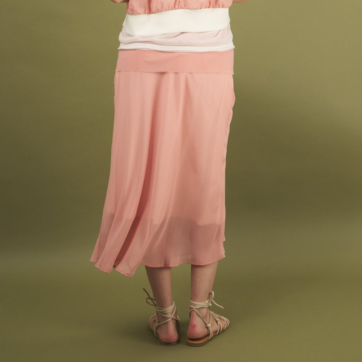 a coral midi length slay skirt by inlarkin back view with a sheer layer at the hem and side pockets