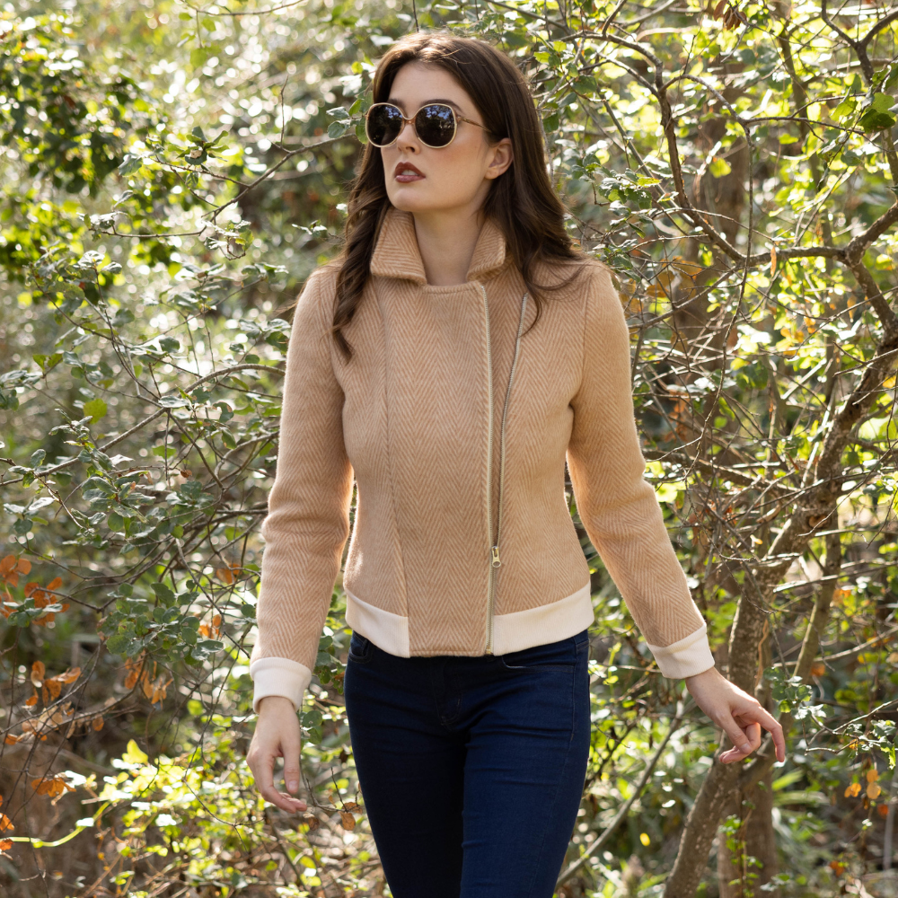  woman in lush landscape wearing the wool bomber jacket in coffee by inlarkin paired with the unreal jean 2.0 in dark wash 