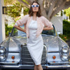 model standing in front of a vintage gray mercedes benz convertible wearing a form fitting white mariposa dress and coral beauty bomber jacket by inlarkin
