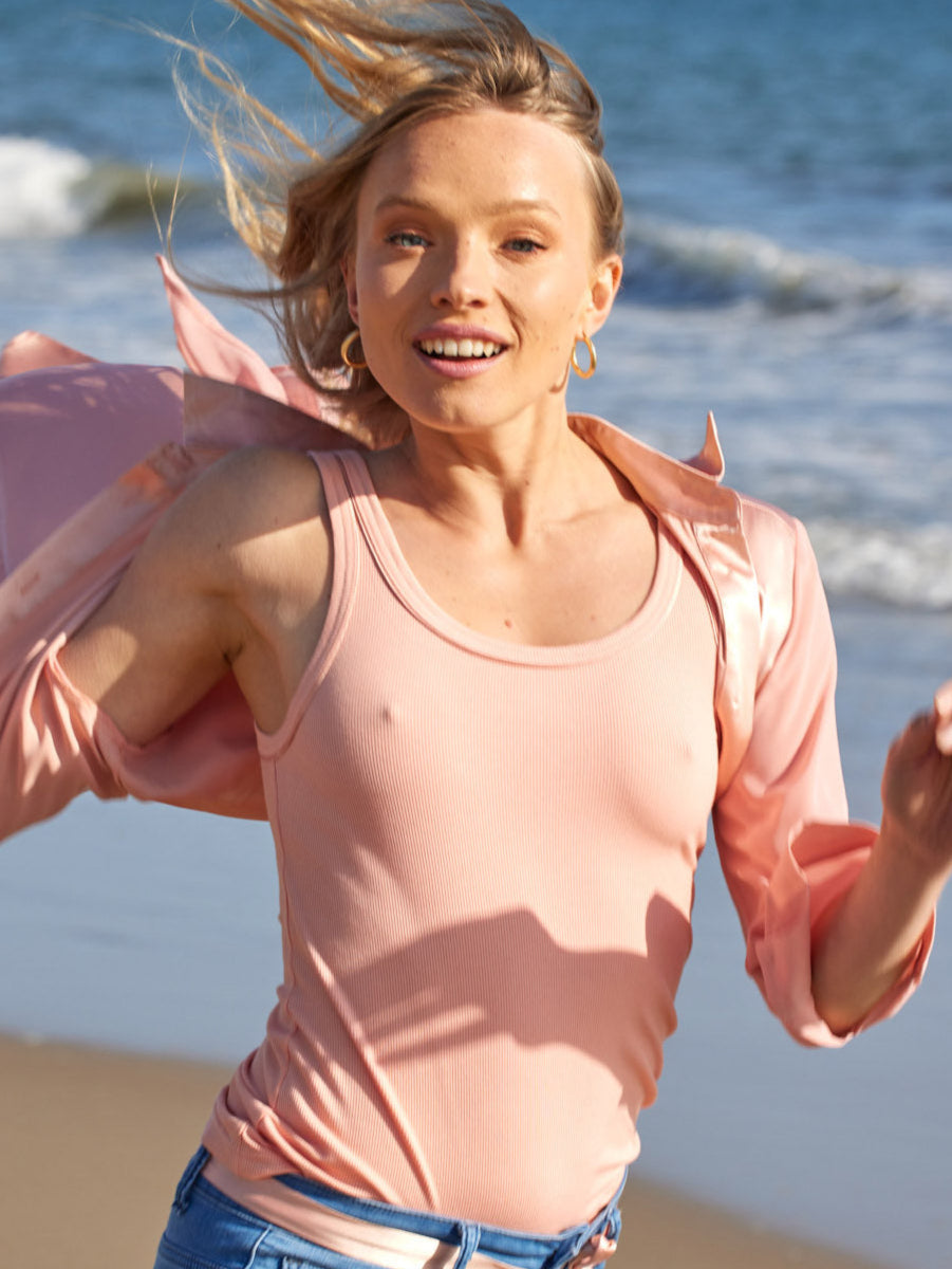 model running on the beach wearing the variegated tank 2.0 in coral by inlarkin with the sateen neck and armhole trim