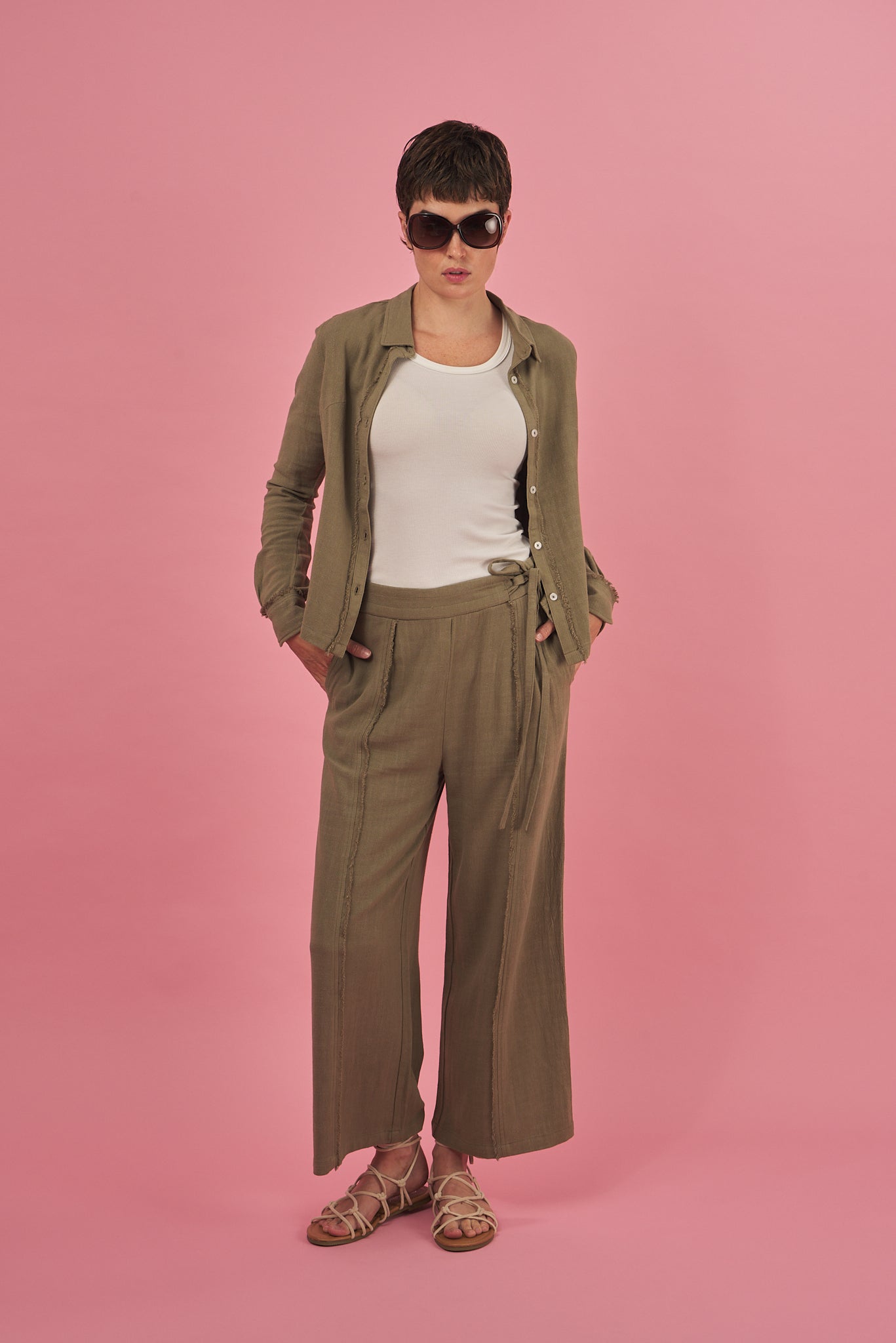 a woman wearing the new arrival sage green fray pant and shirt by inlarkin on a pink background