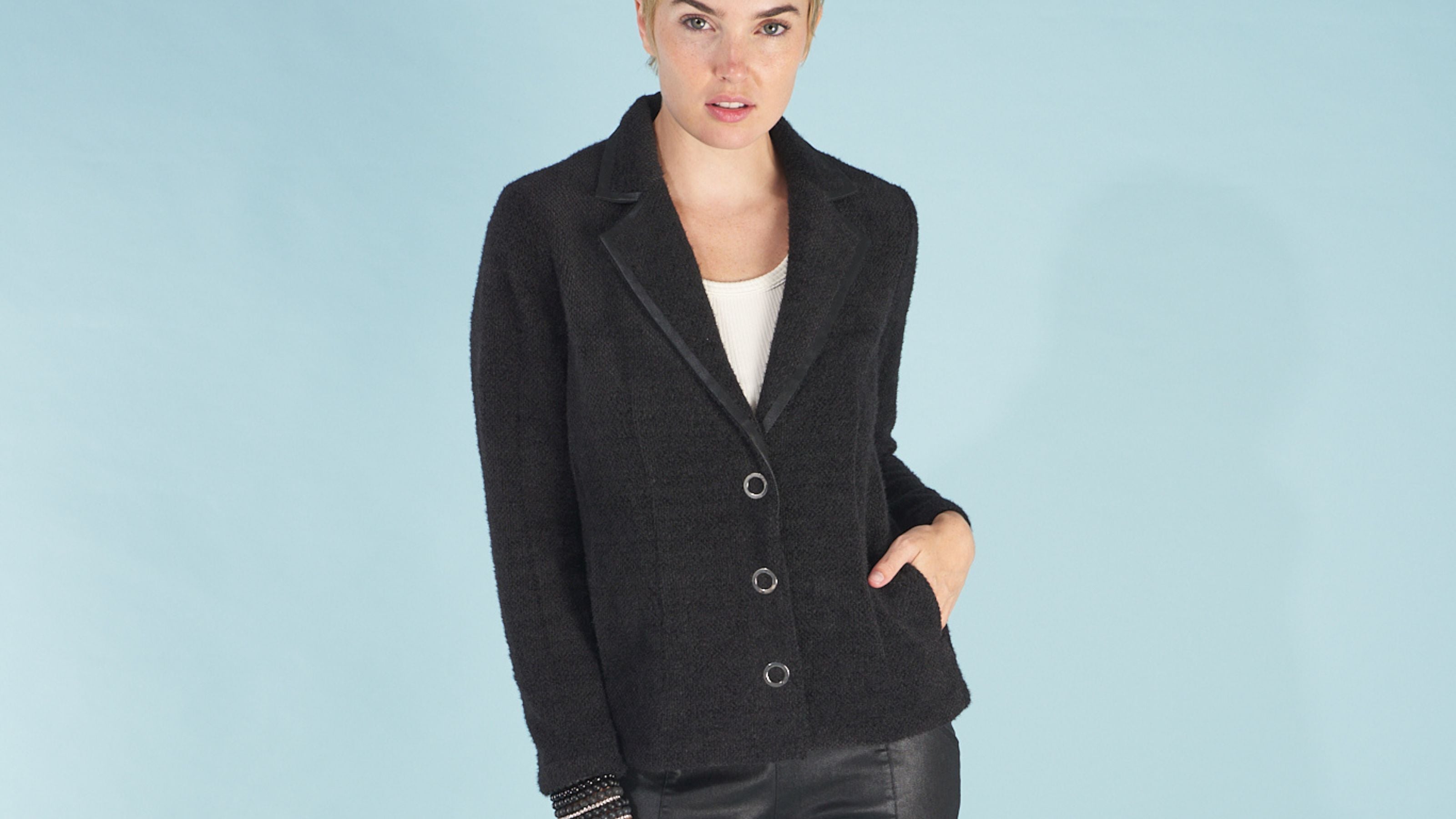 Woman wearing a black austin blazer by inlarkin against a light blue background