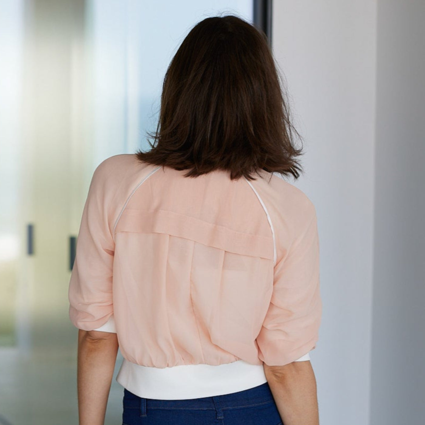 woman wearing a coral beauty bomber by inlarkin showing the vent in the back and piping
