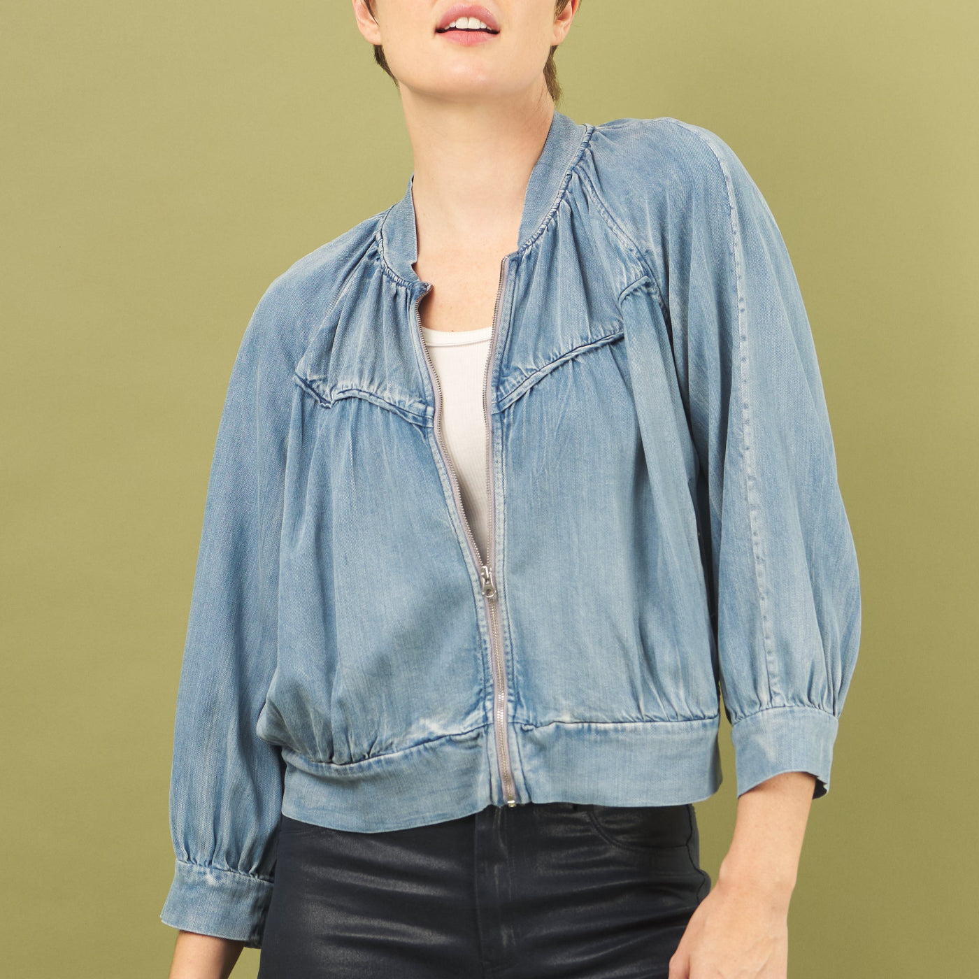 Person wearing a light blue denim jacket on a green background