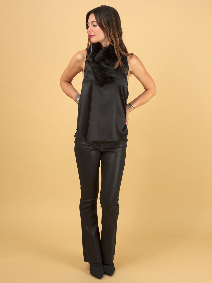 a woman wearing a black decuir silk shell by inlarkin with black gloss curve jeans on a yellow background