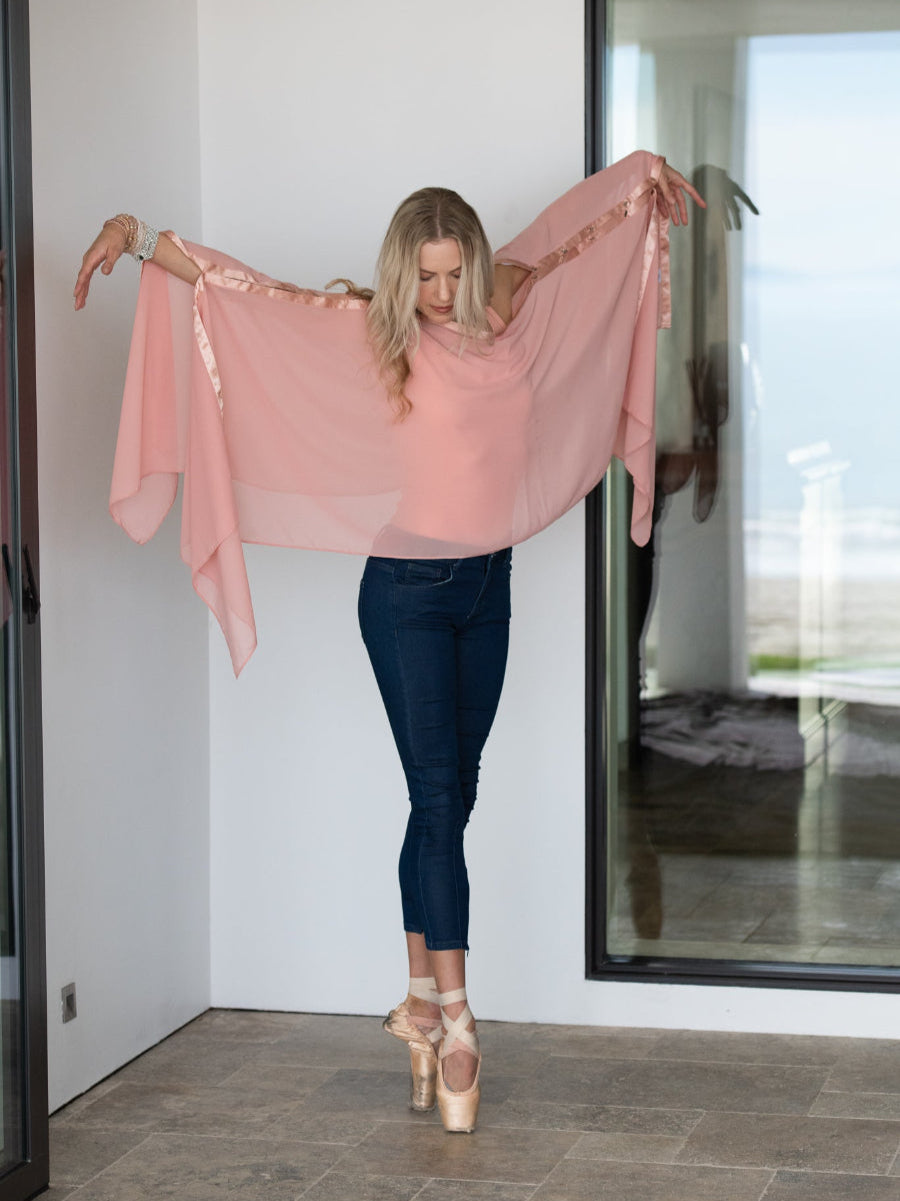 Woman holding a pink sheer top in front of a mirror