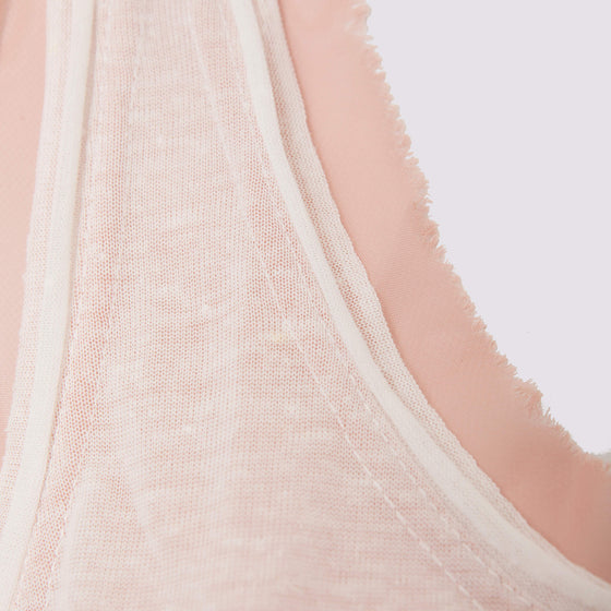 detail view of the glasswing shell 2.0 in coral by inlarkin showing the detailed raw edge hem at neckline 