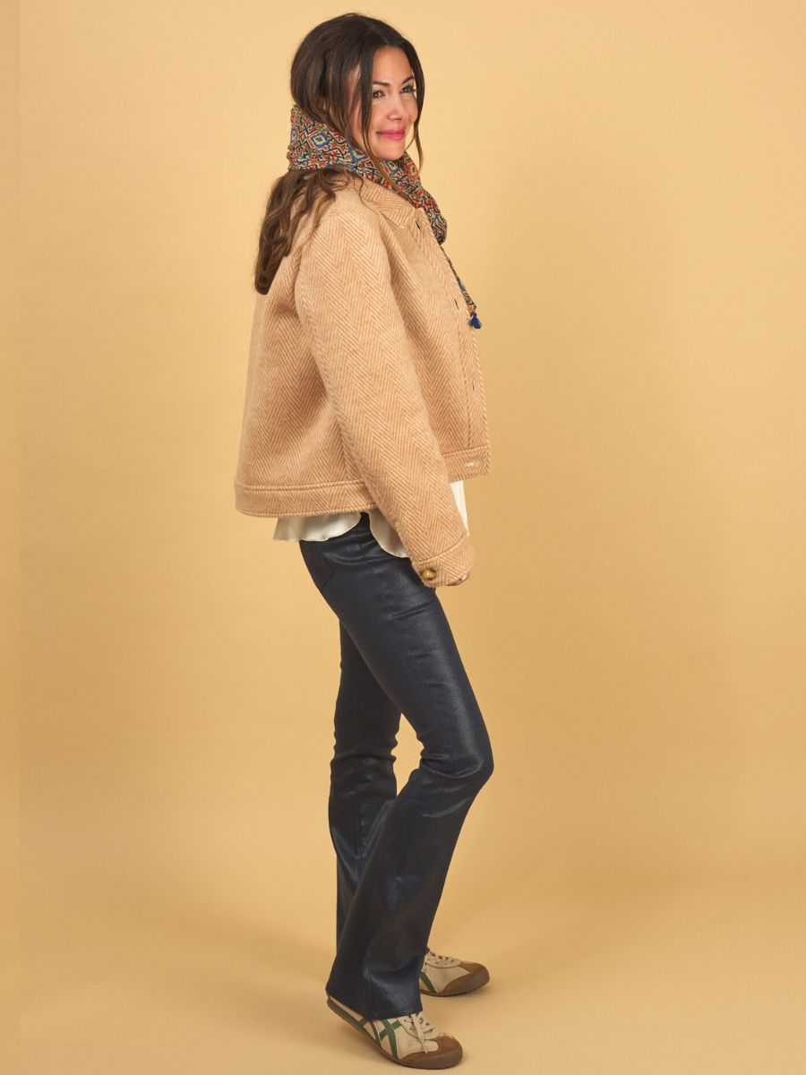 woman wearing a silk shell, herringbone jacket and gloss curve jean in navy by inlarkin on a yellow background