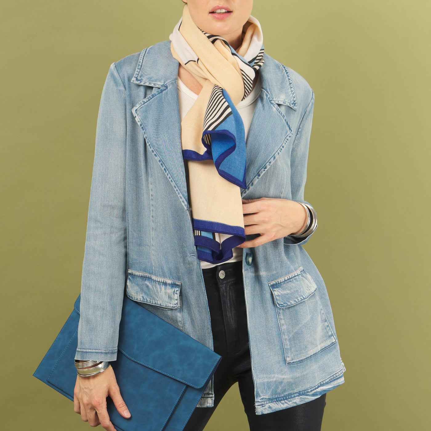 Woman wearing a denim jane jacket by inlarkin and a  scarf against a green background