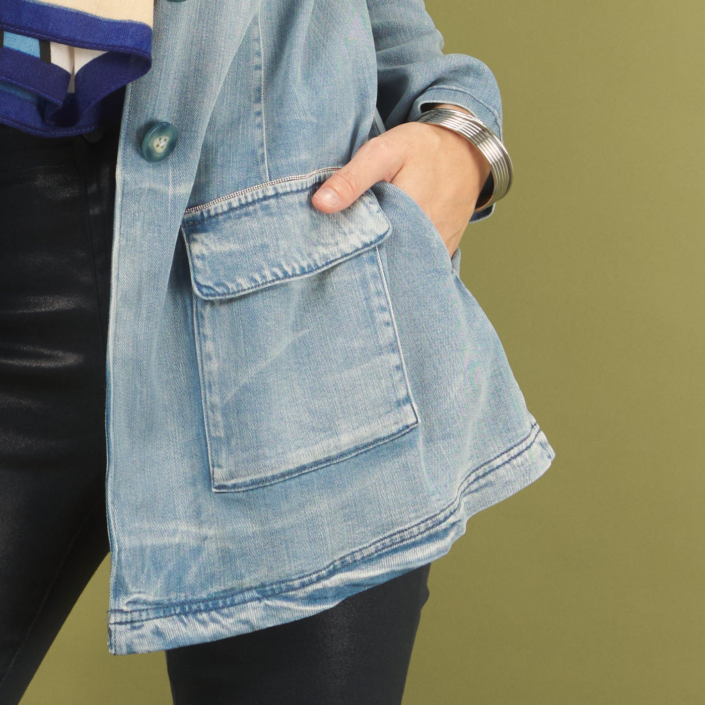 Person wearing a light blue denim jacket with a green background
