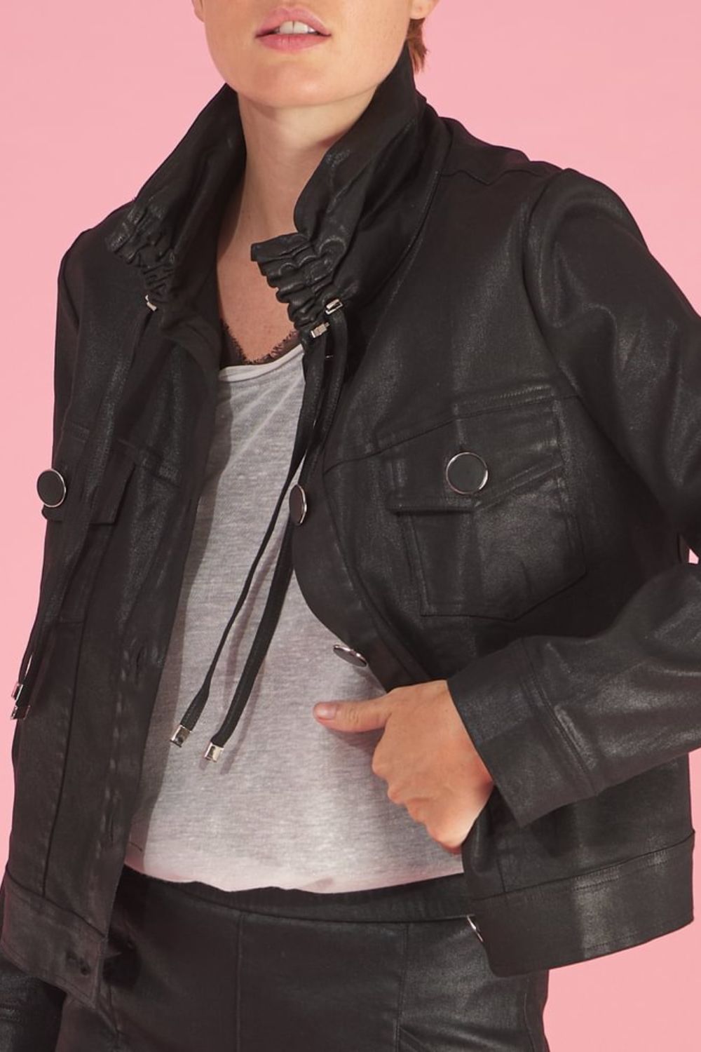 Person wearing a black juju faux leather jacket by inlarkin against a pink background
