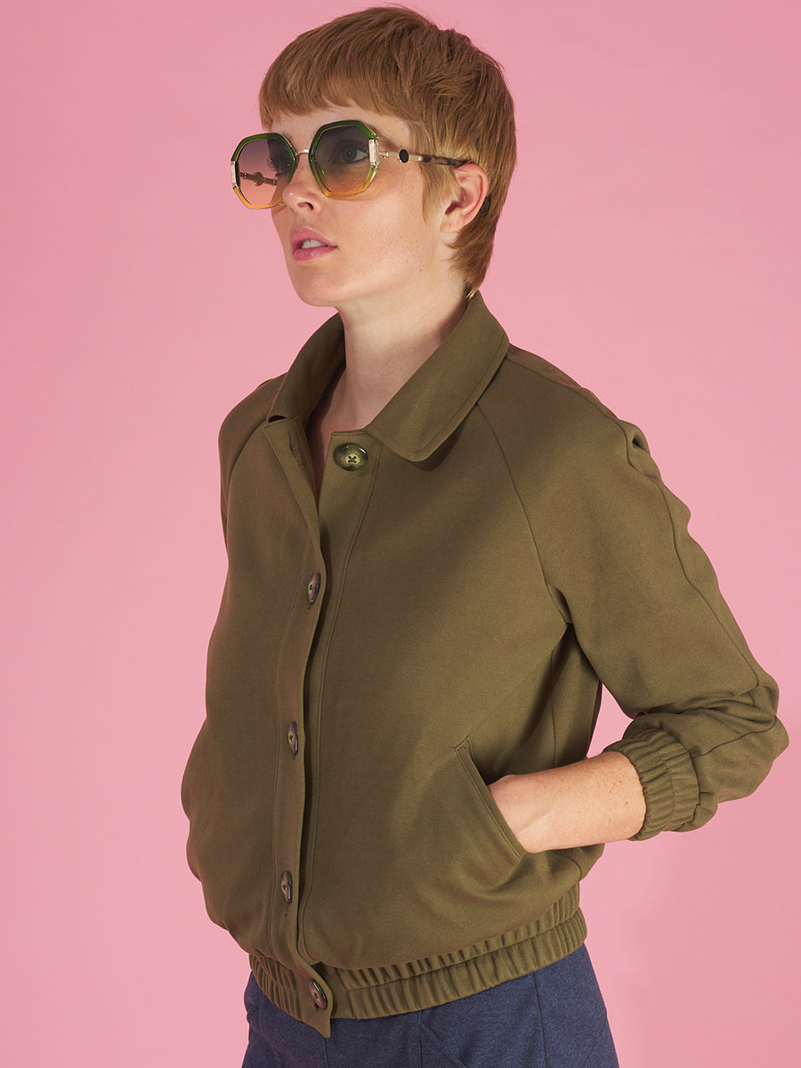 lady bomber jacket side view in olive by inlarkin showing the seaglass buttons, butterfly collar, pockets and gathered hem