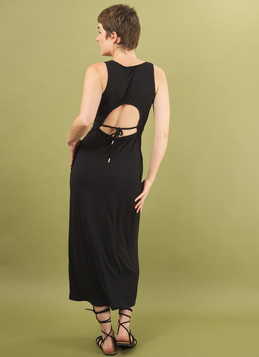 back view of a woman wearing a black dress with cut-out design on a green background