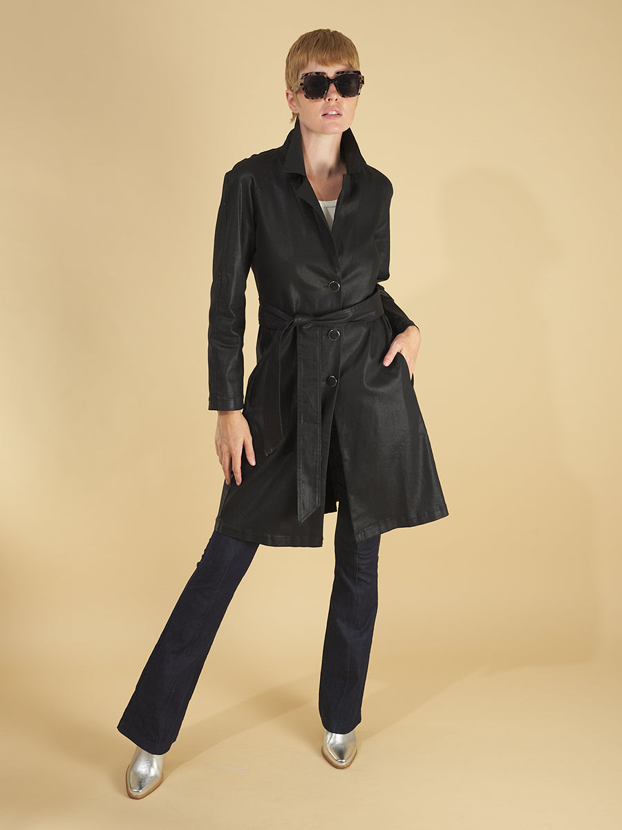 the toni trench coat by inlarkin in black front view showing the high gloss fabric, collar, side seam pockets and belt, paired with the sublime jean