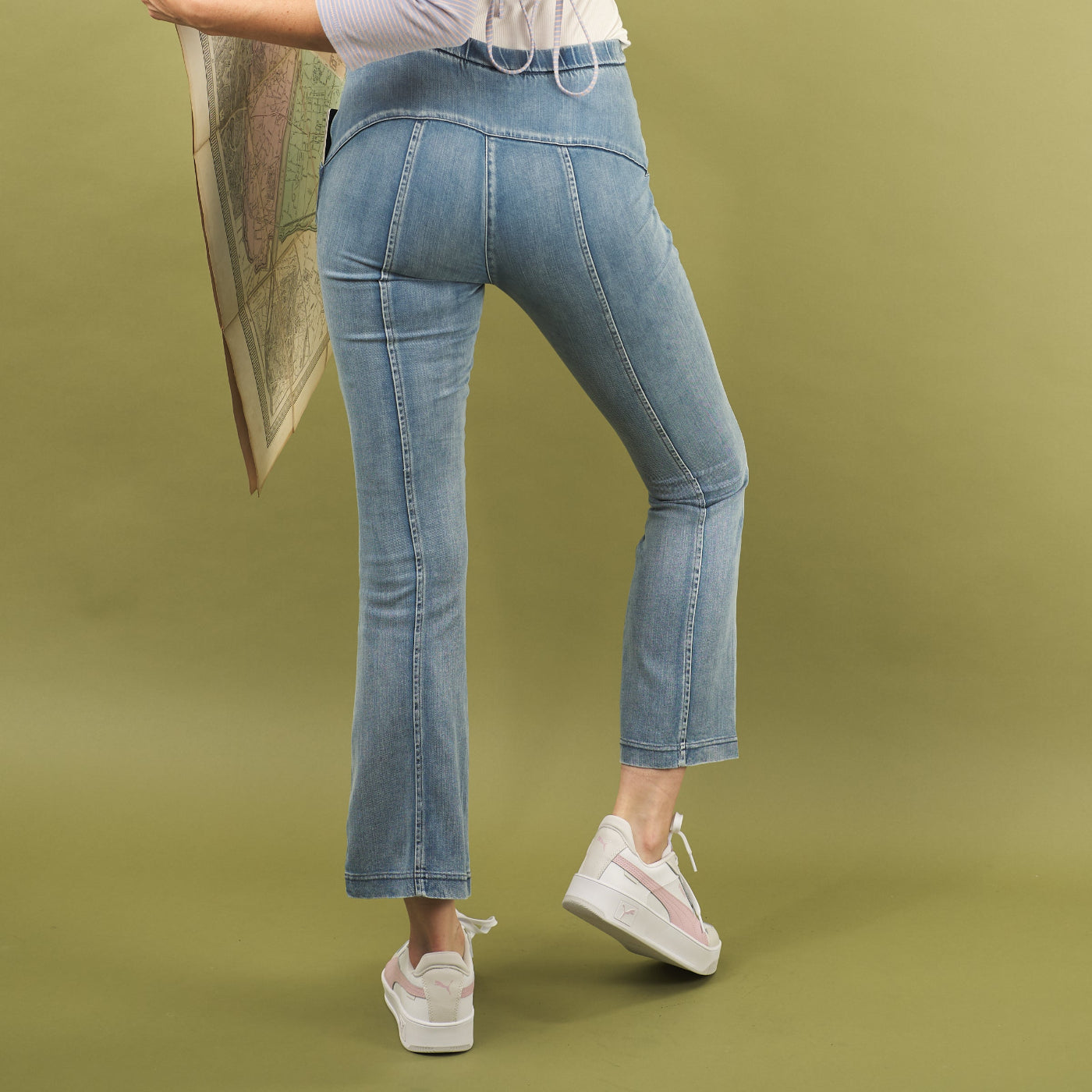 woman wearing the water jean by inlarkin with a flattering fit and seam detail down the legs on a green background