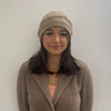woman wearing the cashmere beanie in camel showing the frayed edge folded and versatility of the beanie