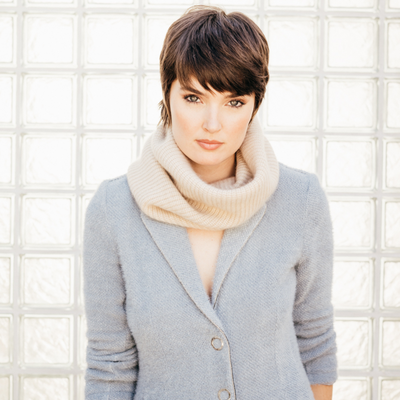 woman wearing a blue blazer paired with the cashmere neck warmer in wheat showing its ribbing and softness detail