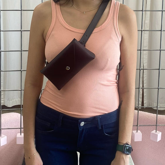 detail image of the inez purse belt by inlarkin in brown worn across the chest as a crossbody purse with a tank top and jeans