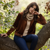 woman sitting in a tree wearing the inlarkin velour jackie jacket in coffee showing the richness of the fabric, the details of the belted waist and the generous collar
