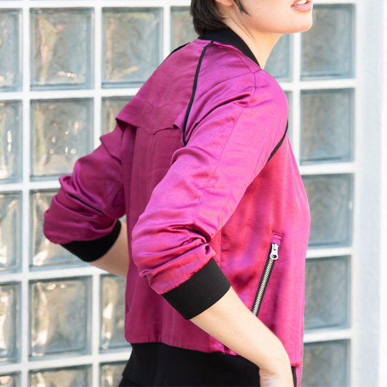 model wearing a fuchsia olivia beauty bomber jacket with black trim and functional front pockets with zippers by inlarkin