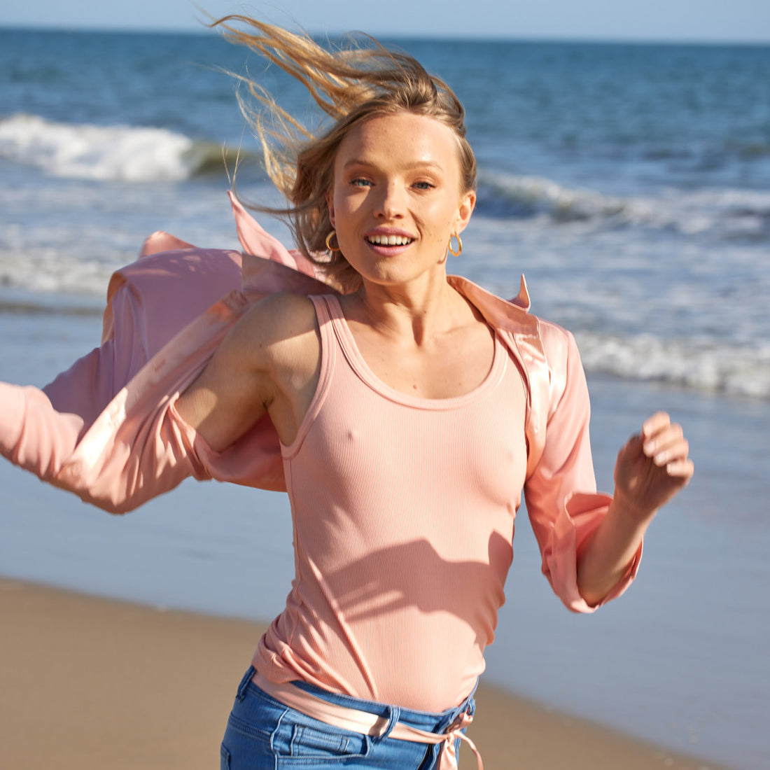  model running on the beach wearing the variegated tank 2.0 in coral by inlarkin with the sateen neck and armhole trim