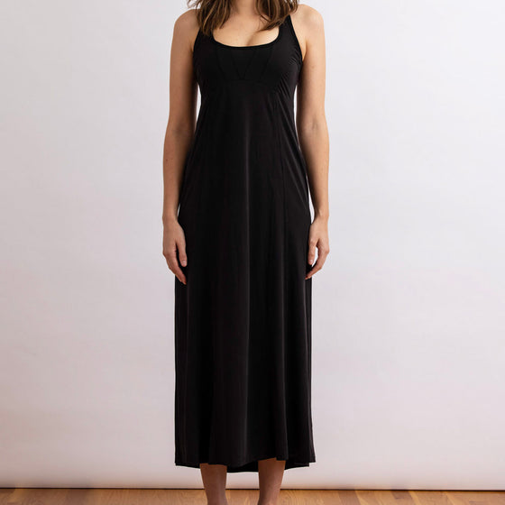 full front view of the wingspan dress in black by inlarkin showing the fitted top and drape flow from the waist down
